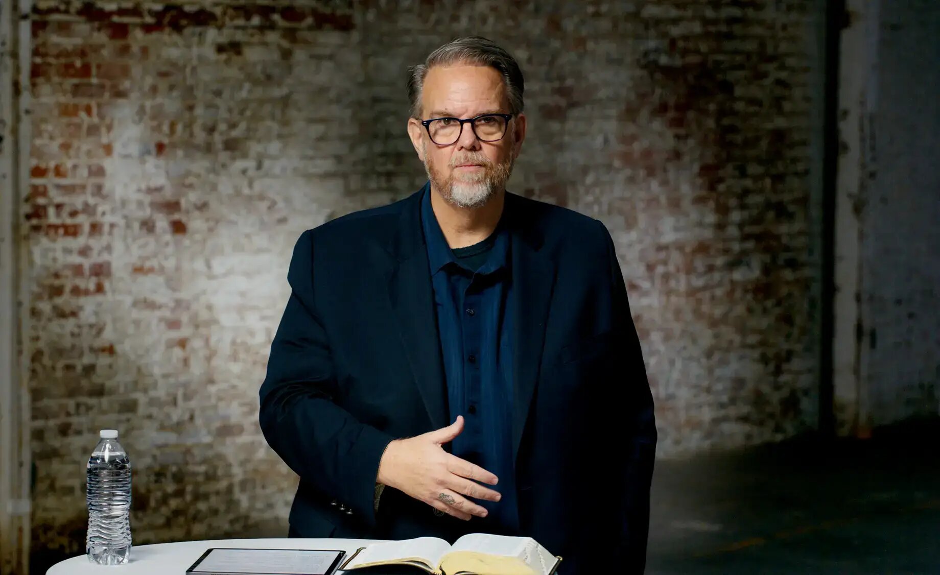 Ed Stetzer standing beside an open Bible in front of a brick wall